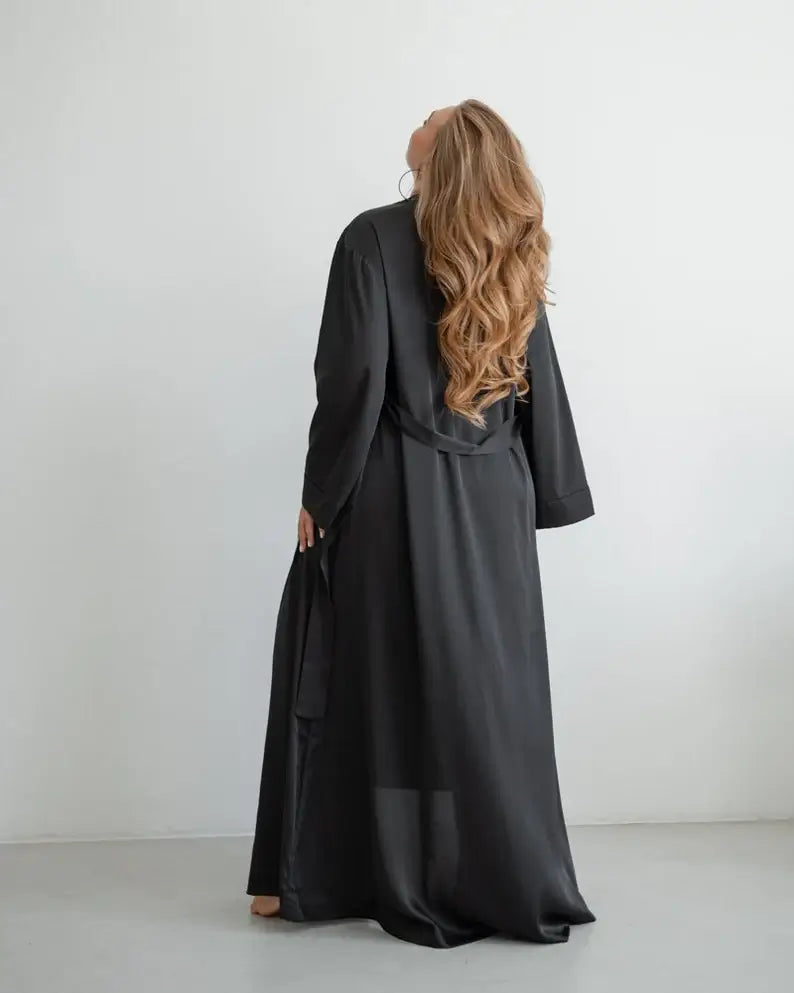 Person wearing a long black dress with a plain white background